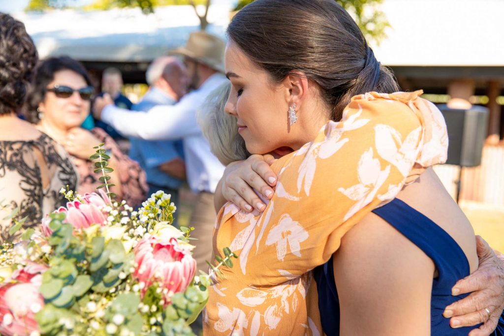 Bridesmaid embraces guest at wedding.