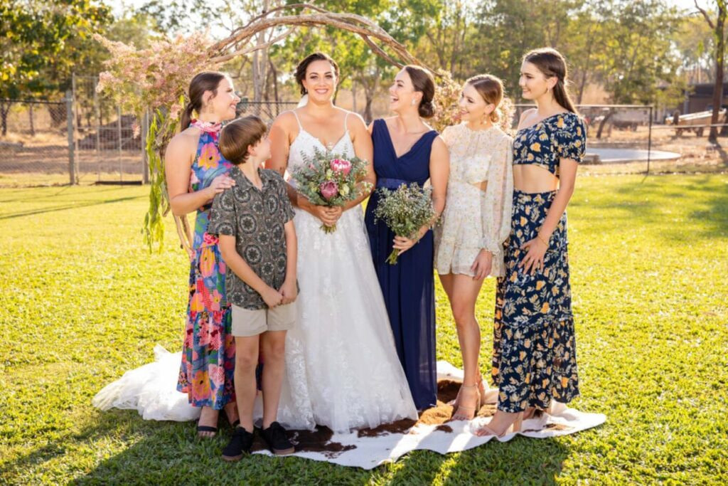 Bride poses with family under the wedding arch. At the Bark Hut Inn NT.