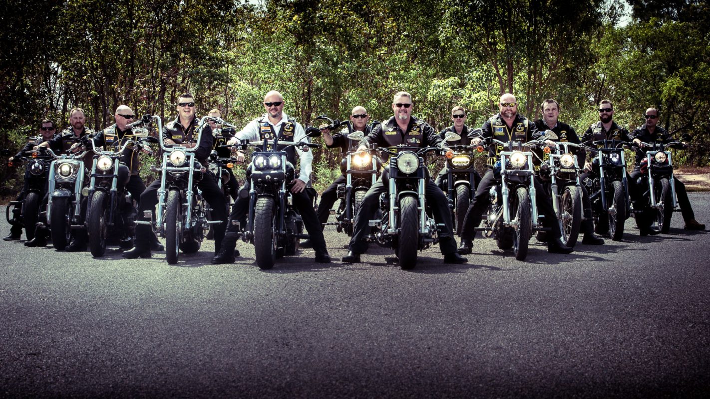 Groom sits on motorcycle with his Veterans club members lined up in formation.