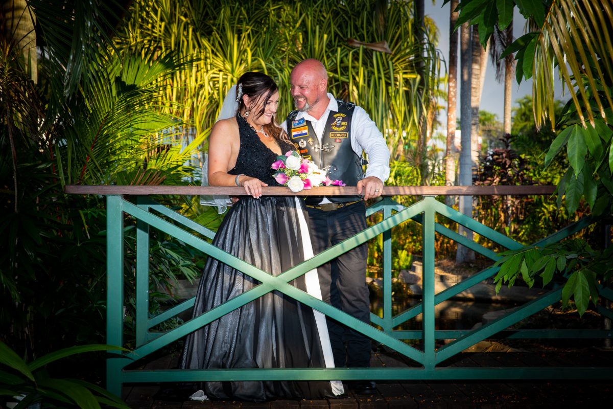 Bride and Groom share a joke standing on a small bridge.