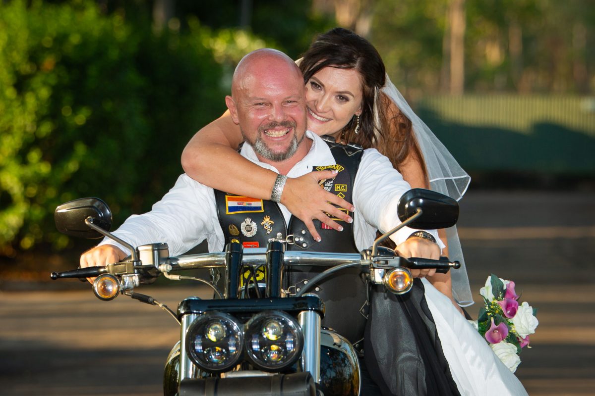 Wedding couple pose on a Harley Davidson motorcycle.