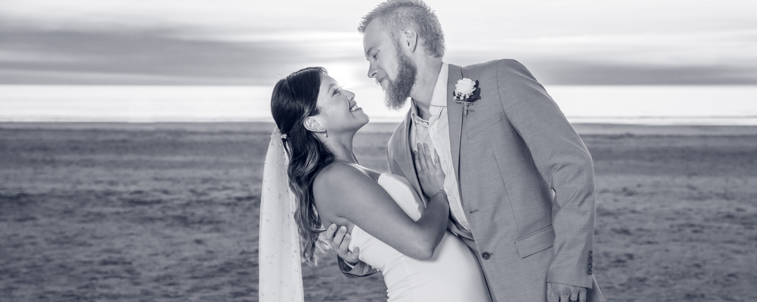 Groom dips his bride at Lee Point Beach Darwwin at sunset black and white