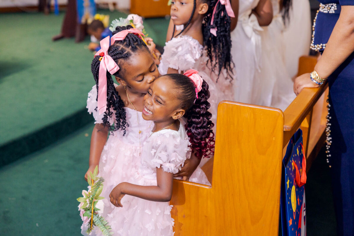 Young bridemaid embraces younger sister